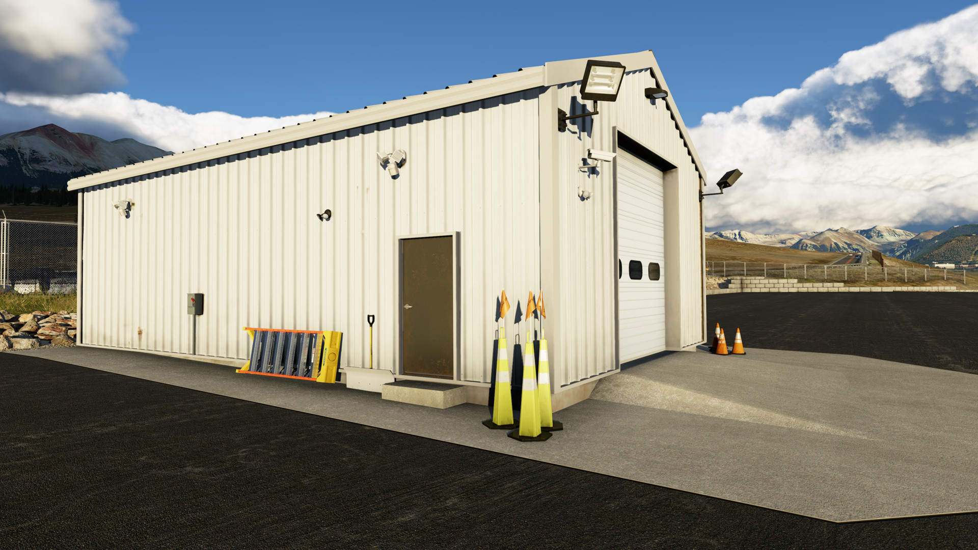 Shed at Telluride Regional Airport ramp in X-Plane 12 that is elevated with ramp leading to the garage door. Background shows mountains and retaining walls on the ramp