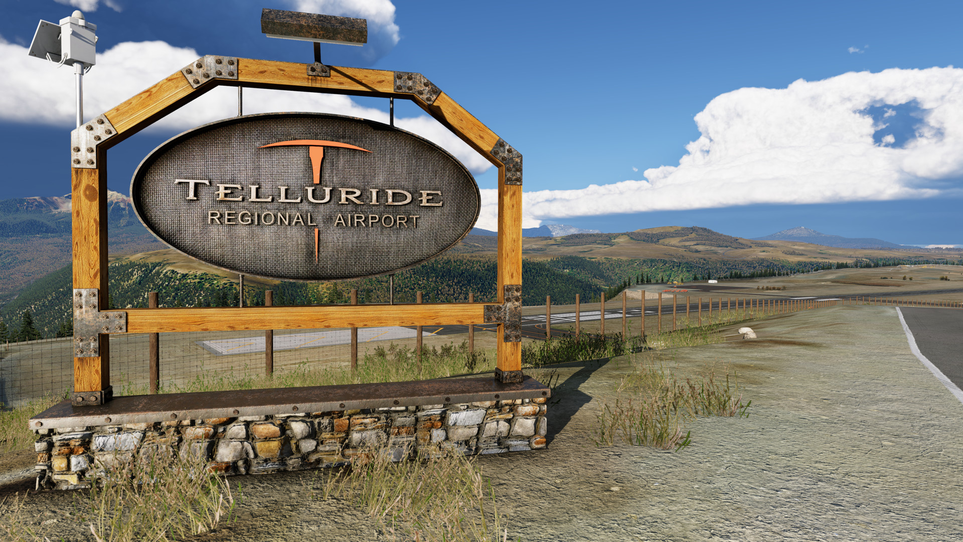 Large metal Telluride Regional Airport sign on the road leading to KTEX with runway 27 in the background below X-Plane 12